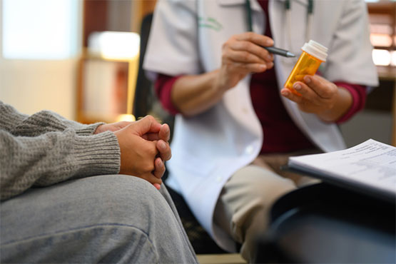 A provider shows a prescription medicine bottle to their patient