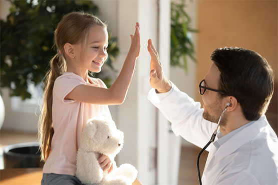 A little girl with a stuffed toy high fives her doctor