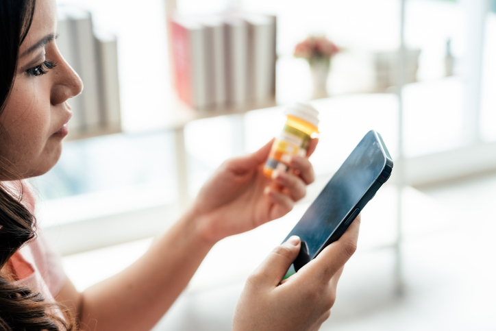 A woman examines a bottle of prescription medicine